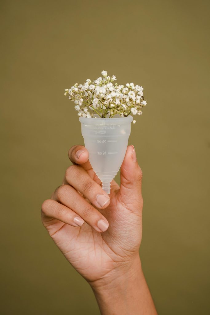 pexels-photo-5938647-5938647 Minimalistic photo of a hand holding a menstrual cup with delicate flowers, symbolizing eco-friendly menstruation.