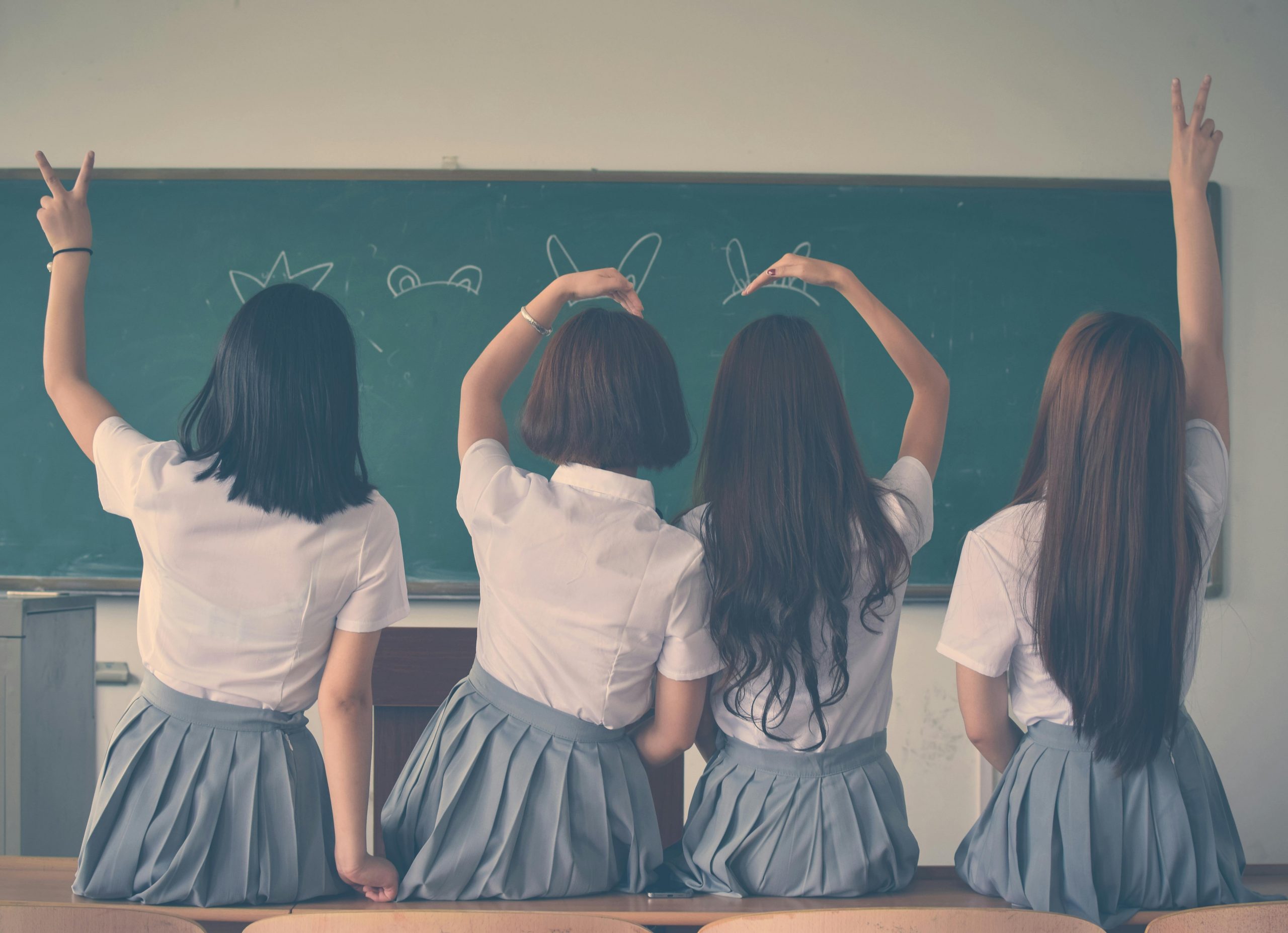 pexels-photo-710743-710743 Group of teenage girls in school uniforms enjoying time together in a classroom, posing with playful gestures.