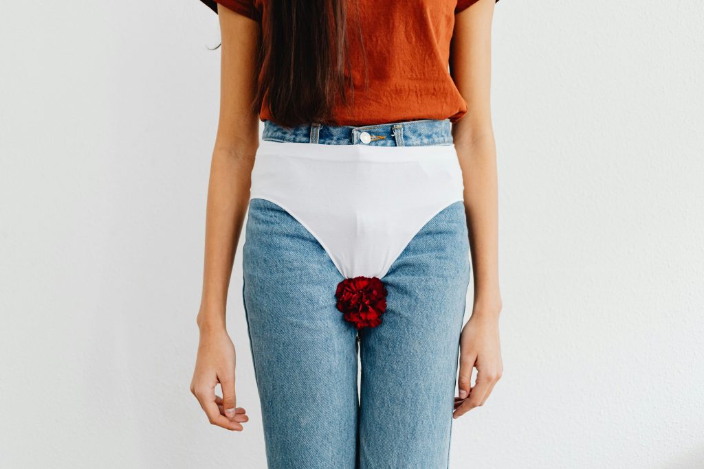 pexels-photo-7281777-7281777 Symbolic representation of menstruation using red flower on jeans, addressing social issues.