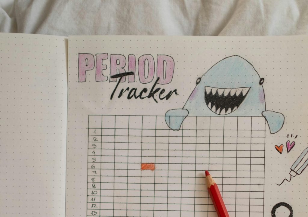Creative period tracker notebook with a hand holding birth control pills.