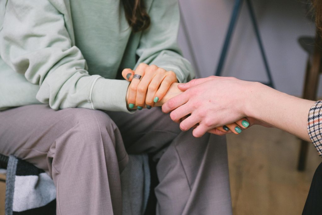 pexels-photo-7176325-7176325 Close-up of two people holding hands during a comforting therapy session.